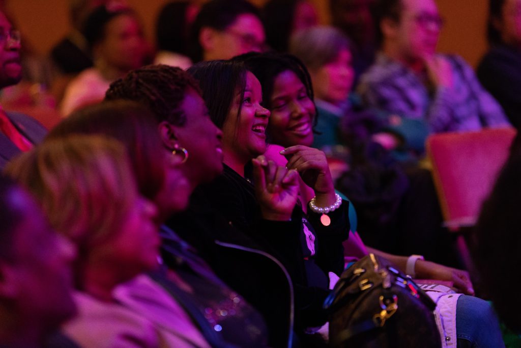 Members of the audience laugh while watching T. Murph perform.