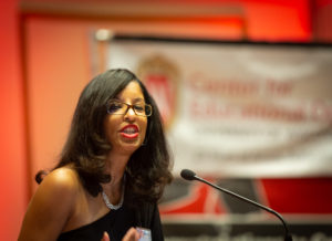 CeO Director Claudia Mosley speaks into a microphone at a podium with a banner in the background bearing the logo of the Center for Educational Opportunity.