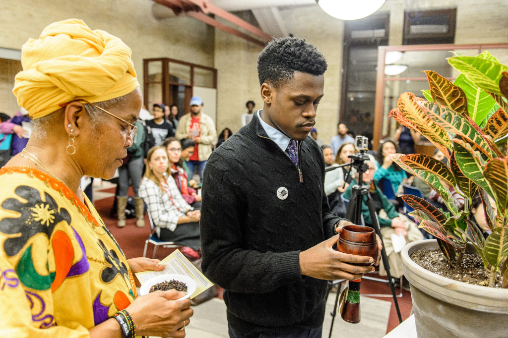 Hazel Symonette (left), program development and assessment specialist in the Division of Student Life, and Marquise Mays (right), chair of the Wisconsin Black Student Union, perform a libation pouring ritual in memory of those who have passed on during a dedication and libation ceremony for the new Black Cultural Center at the University of Wisconsin-Madison on Feb. 28, 2017. (Photo by 