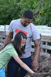 Dantrell Cotton instructing the "You Are What You Eat" middle school workshop field trip to the University Houses Community Garden for the PEOPLE program, Photo by Valeria A. Davis
