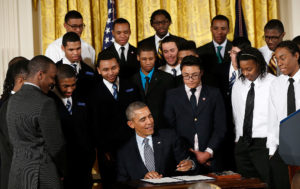 President Barack Obama at the signs the "My Brother's Keeper" Initiative surrounded by the young men it will serve.  Photo from U.S. Historical files 
