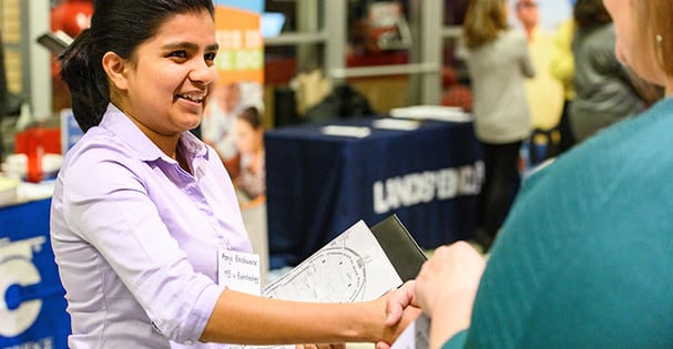 A student talks and shakes hands with a recruiter during an Internship Fair.