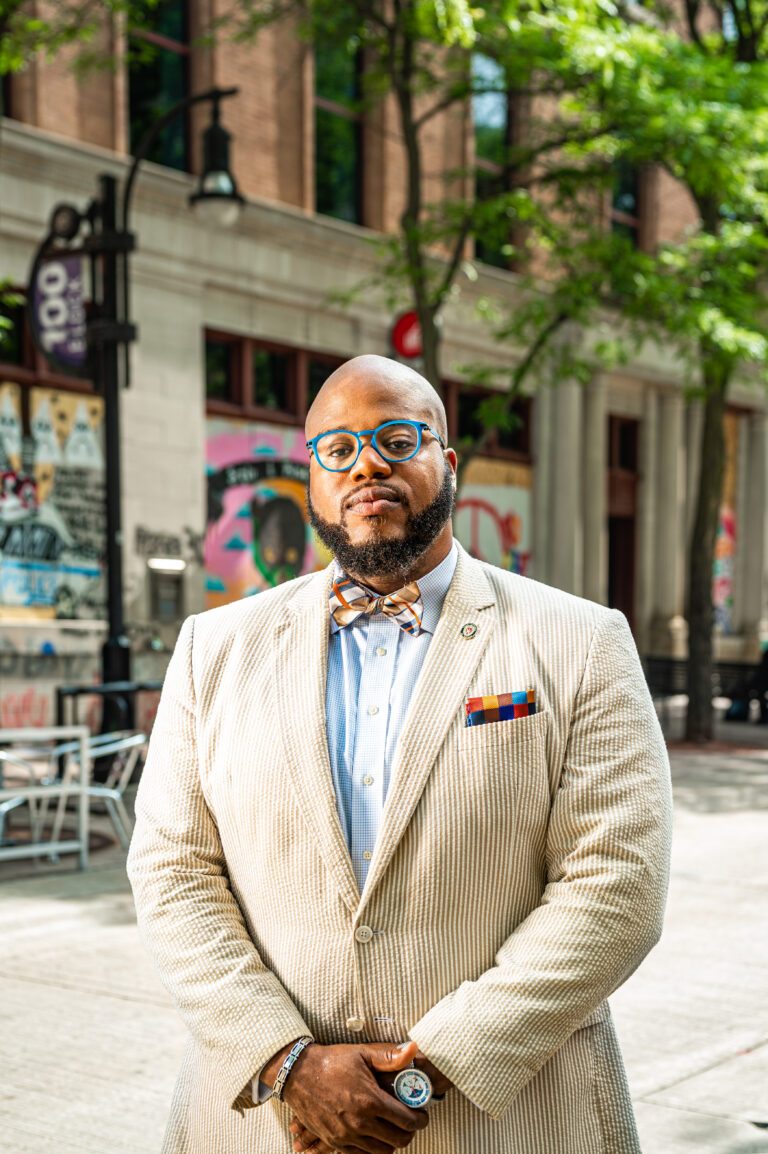 Portrait of LaVar Charleston wearing a white suit and colorful bowtie standing on State Street