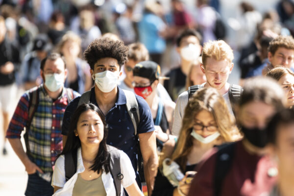 A large group of students walk outside on the UW campus
