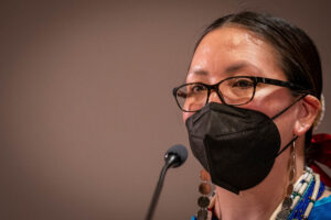 Jennifer Gauthier tears up as she speaks into a microphone.