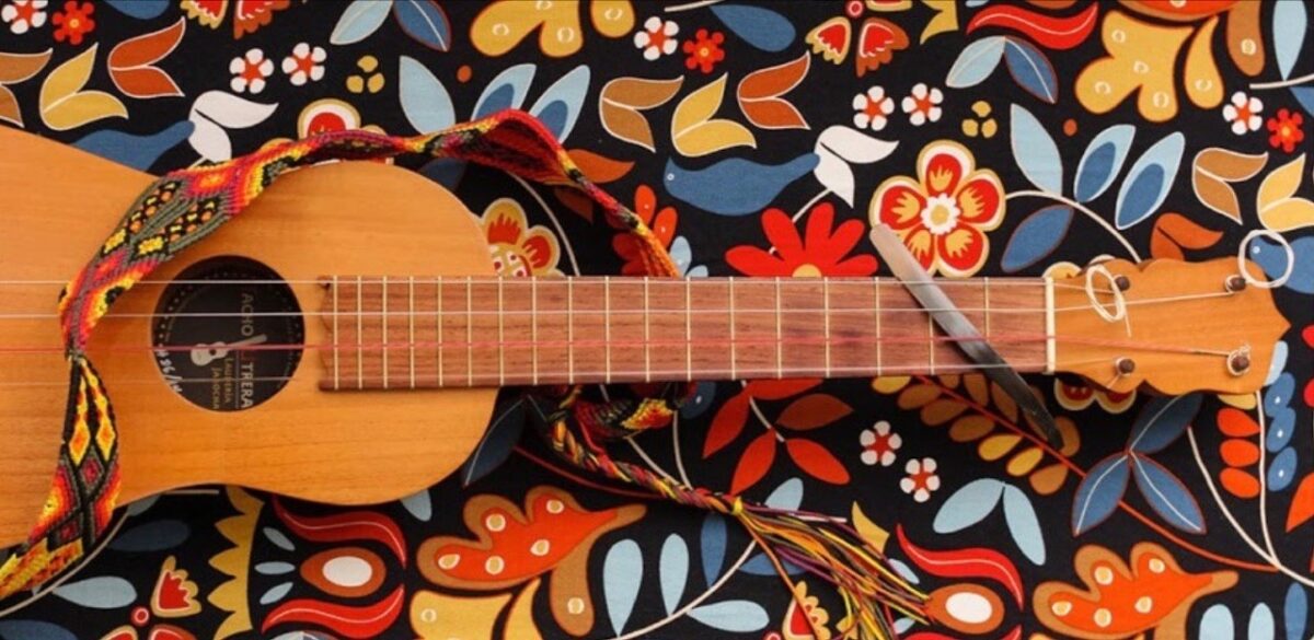 An acoustic guitar sits on a table with colorful floral designs.