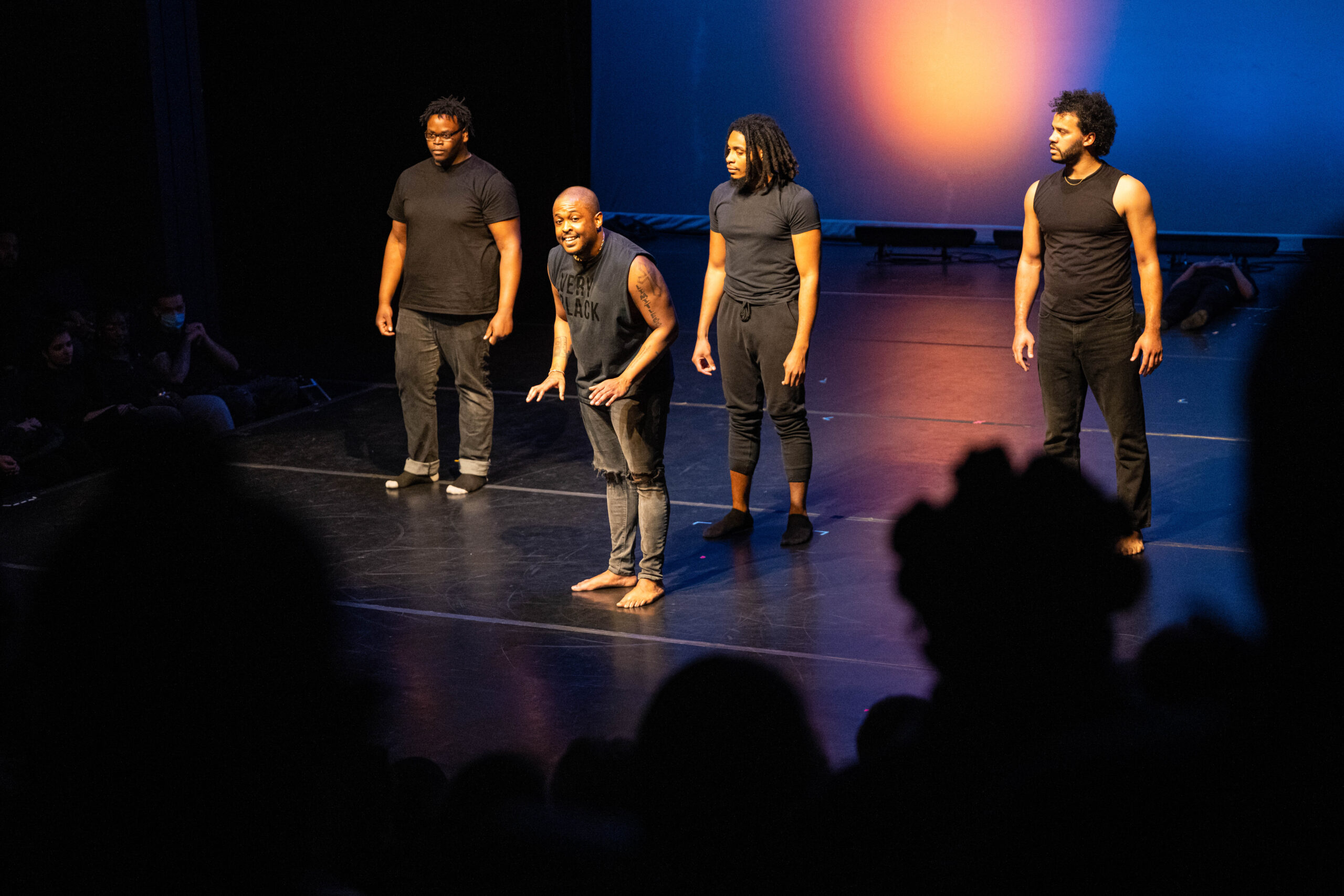 A group of performers dressed in black on stage.